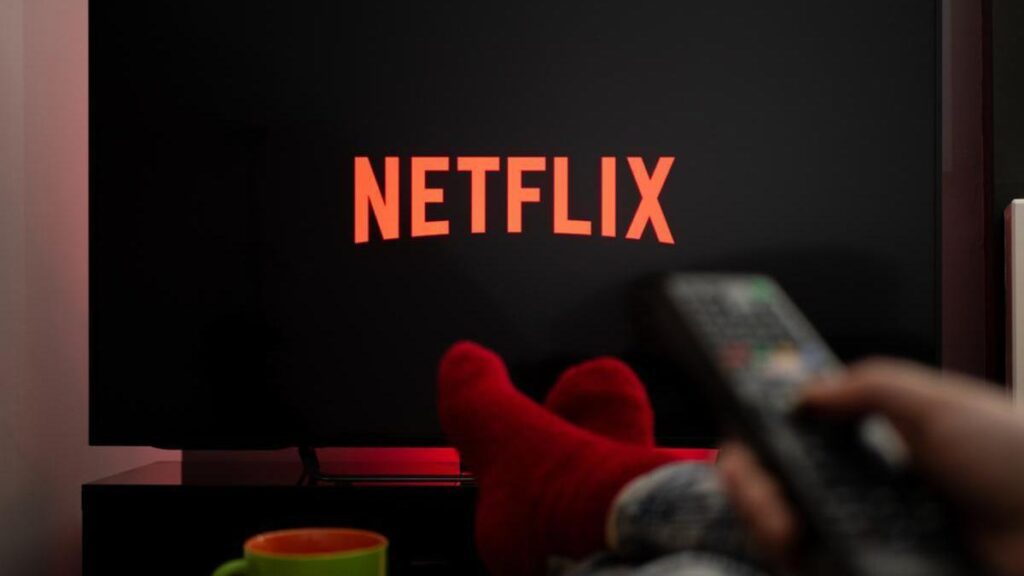 Persona utilizando una plataforma de streaming para escoger una serie o película en un televisor.