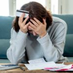 Mujer revisando sus cuentas y finanzas personales, una escena que representa la fragilidad financiera, el endeudamiento y la importancia del ahorro y la planificación económica.