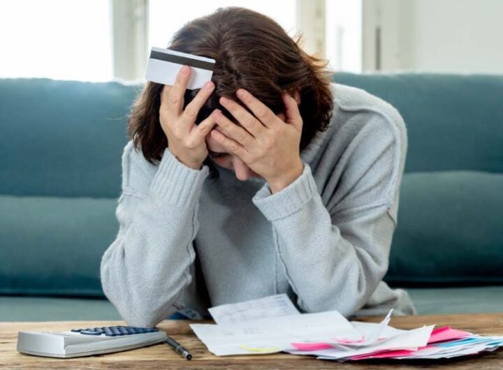 Mujer revisando sus cuentas y finanzas personales, una escena que representa la fragilidad financiera, el endeudamiento y la importancia del ahorro y la planificación económica.