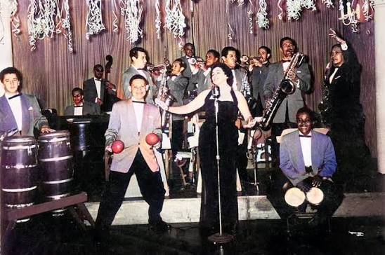 Gran orquesta tropical latinoamericana interpretando música en vivo durante la época dorada de las fiestas populares, símbolo del legado musical de agrupaciones como Billo's Caracas Boys, Los Melódicos y la Sonora Matancera.