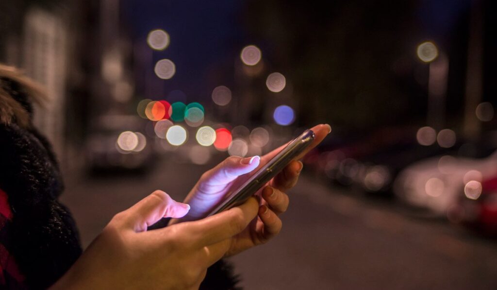 Persona utilizando un teléfono inteligente mientras está sola