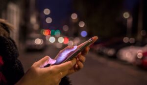 Persona utilizando un teléfono inteligente mientras está sola